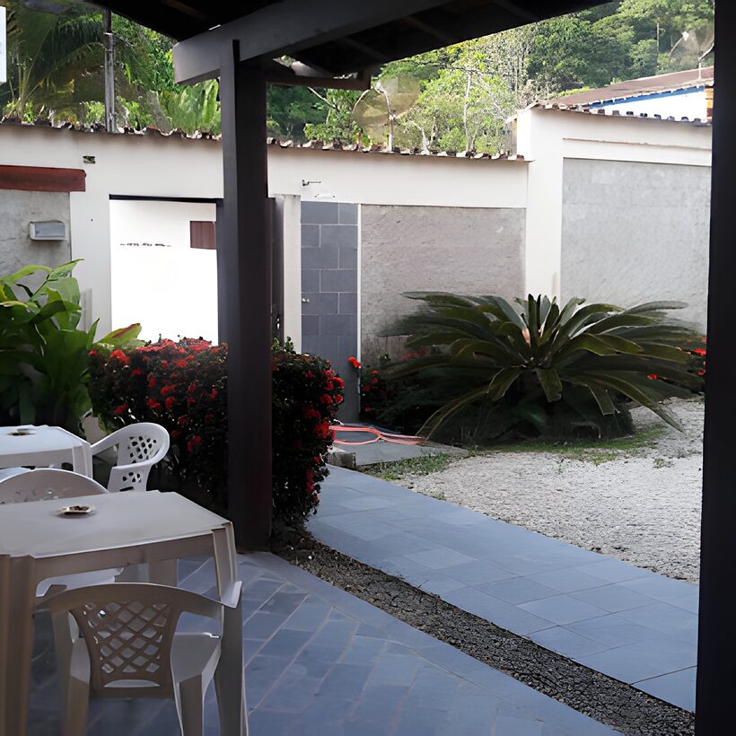 Área externa coberta com mesas e jardim