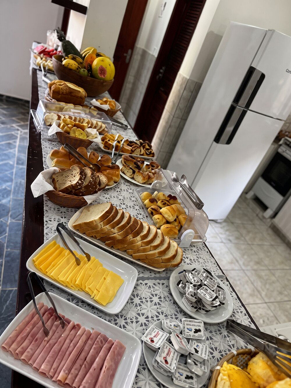 Mesa do café da manhã com pães, bolos, queijos e frutas