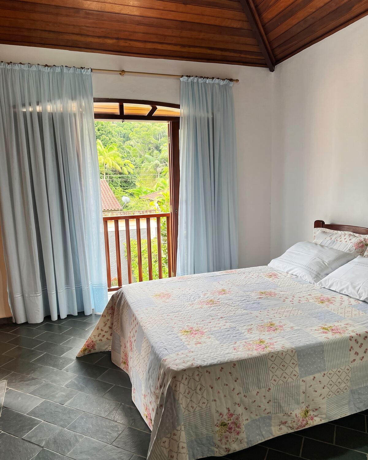 Quarto com porta para a varanda e vista para o verde