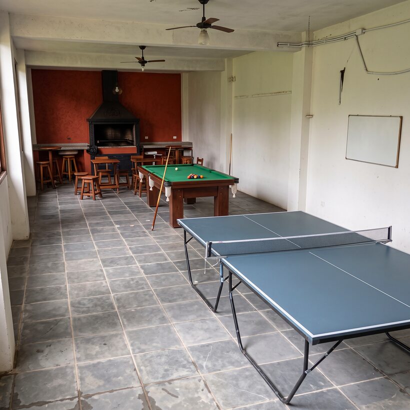 Salão com mesa de ping-pong e mesa de sinuca